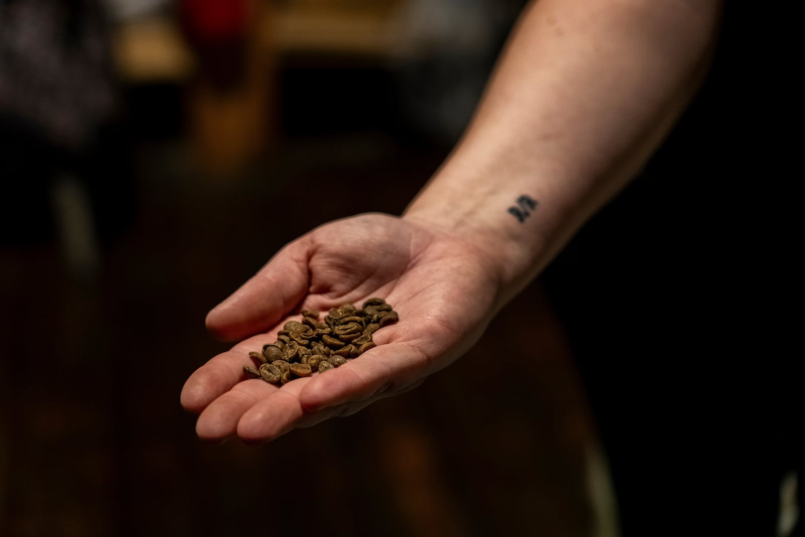 Renee Colon, co-owner of Fuego Coffee Roasters, holds coffee beans while working at her roasting facility, Friday, March 21, 2025, in Rochester, N.Y. (Max Conway via AP)