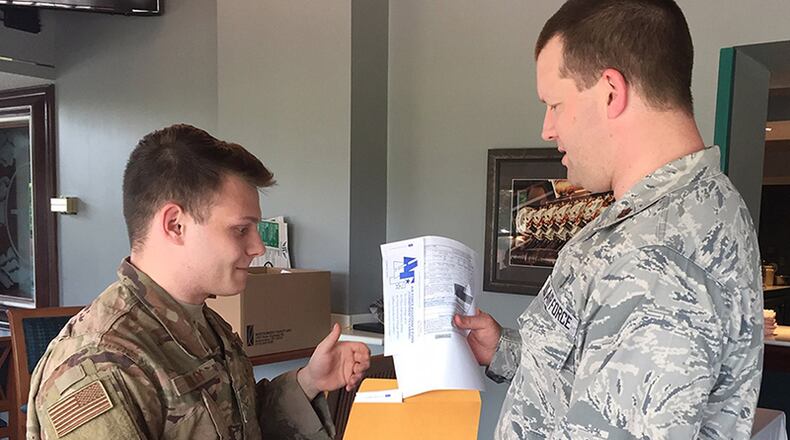 Airman 1st Class Colton Farley (left) turns in pledges and contributions for the Air Force Assistance Fund campaign at Wright-Patterson Air Force Base to Maj. Todd Brackett, installation project officer, May 3 at the Wright-Patterson Club. Farley works in the administrative offices of the Air Force Research Laboratory. (Skywrighter photo/Amy Rollins)
