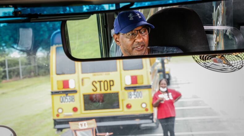 Dayton public schools bus driver in training, Barry Payne, in the mirror, learns to drive a school bus at the Welcome Stadium parking lot Tuesday August 9, 2022. JIM NOELKER/STAFF