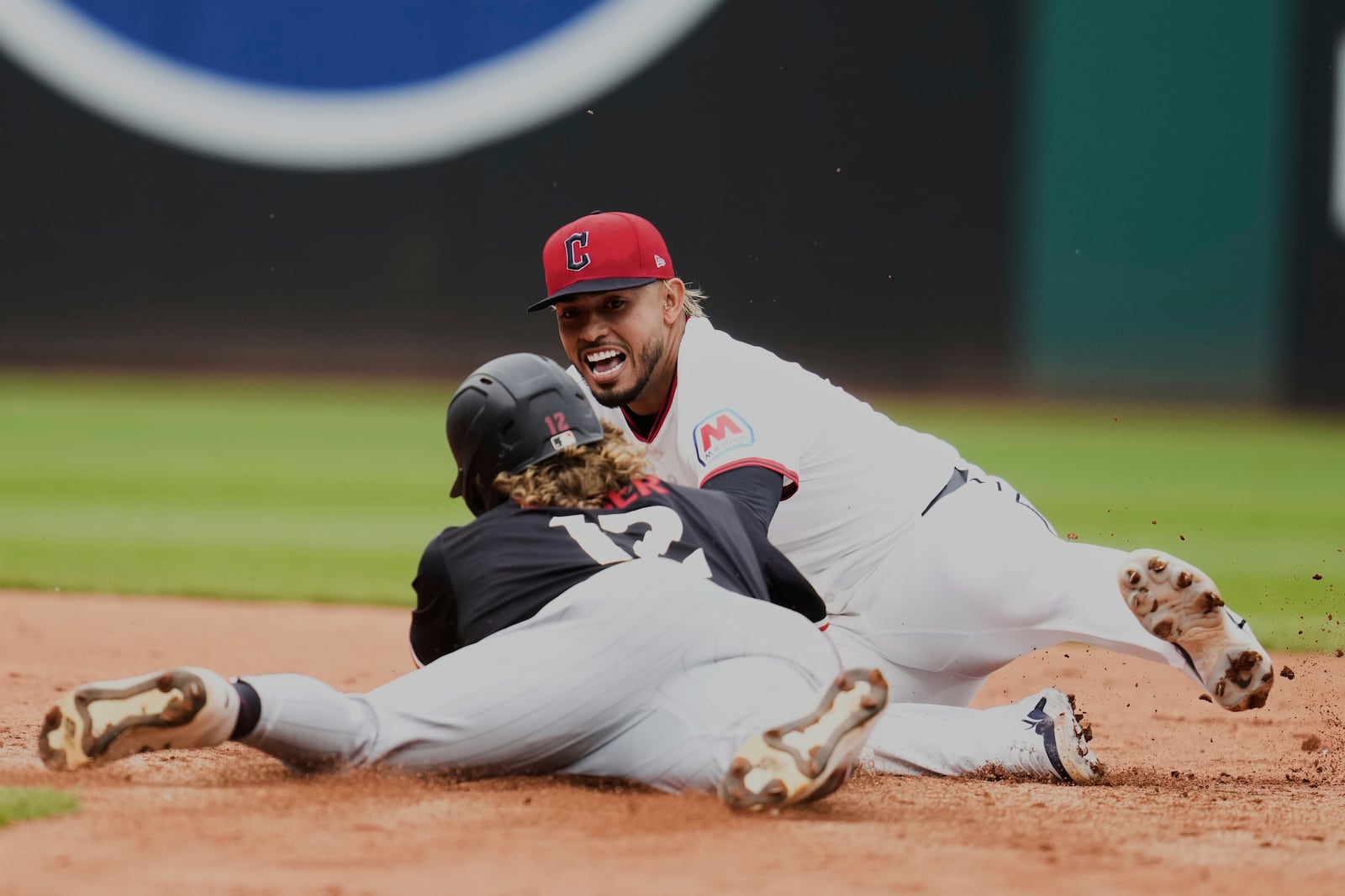 Minnesota Twins' Harrison Bader (12) slides safely into second base in front of Cleveland Guardians second baseman Gabriel Arias, rear, in the seventh inning of a baseball game in Cleveland, Thursday, May 1, 2025. (AP Photo/Sue Ogrocki)