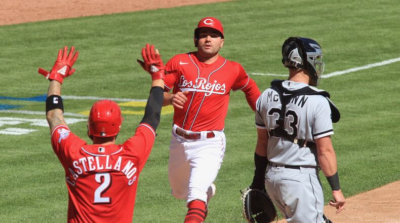 Joey Votto, of the Reds, scores on a single by Mike Moustakas against the White Sox as Nick Castellanos tells Votto not to slide on Sunday, Sept. 20, 2020, at Great American Ball Park in Cincinnati. David Jablonski/Staff