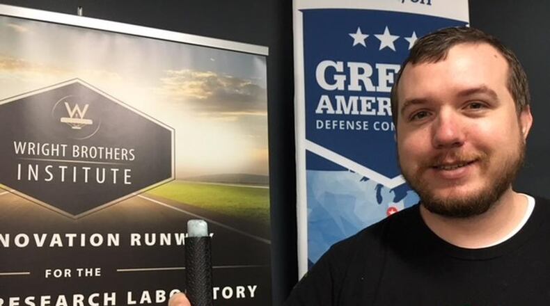 Nicholas Ripplinger, founder and president of Dayton-based Battle Sight Technologies, holding a CrayTac, a reusable glow stick that warfighters and emergency responders can use for covert communication. THOMAS GNAU/STAFF
