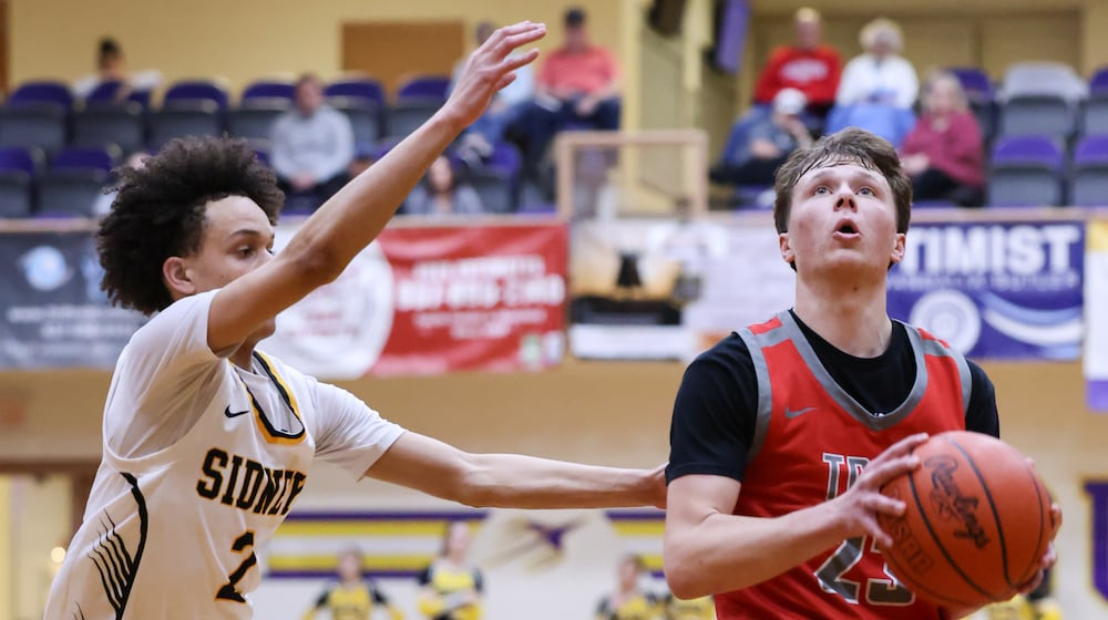 Troy senior guard Josh Murphy shoots with pressure from Sidney's Desean Burns during a Division II district quarterfinal on Friday, Feb. 27 at Vandalia-Butler's Student Activity Center. BRYANT BILLING / STAFF