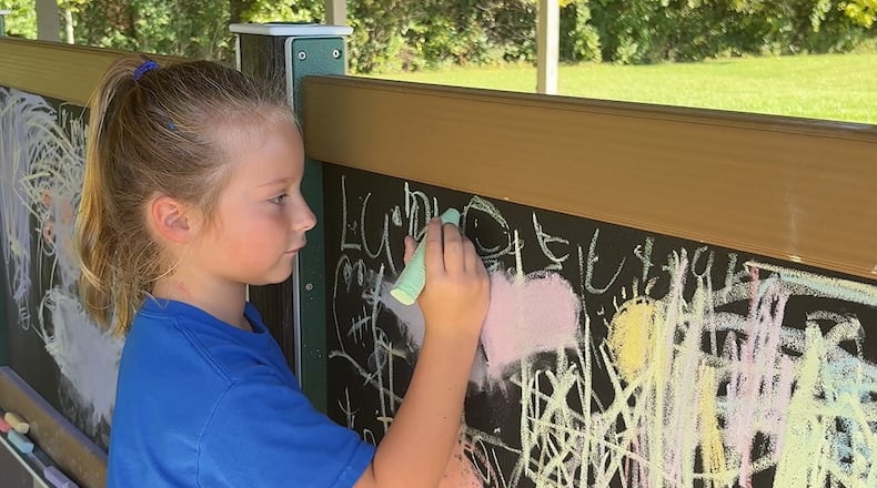 Clearcreek Elementary School student Blakely Moer draws on the magnetic chalkboard Thursday, Oct. 9, 2025, in the new outdoor classroom space in the shelter behind the school in Springboro. JEN BALDUF/STAFF
