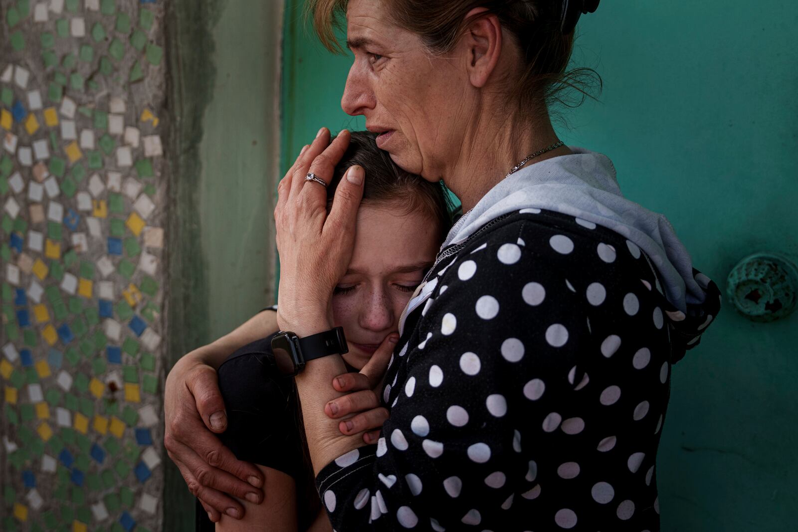 A mother calms her daughter during farewell ceremony of Maksym Martynenko, 11, Natalia Martynenko, 49, Mykola Martynenko, 41, which were killed in a deadly Palm Sunday Russian attack on Sumy on April 13, during farewell ceremony in Stare Selo village near Sumy, Ukraine, April 16, 2025. (AP Photo/Evgeniy Maloletka)