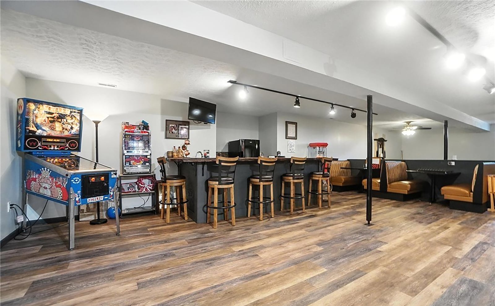 The finished basement has LVT flooring, a wet bar with seating, built in booth seating and track lighting. There is also a game area, bedroom, full bathroom and office. CONTRIBUTED