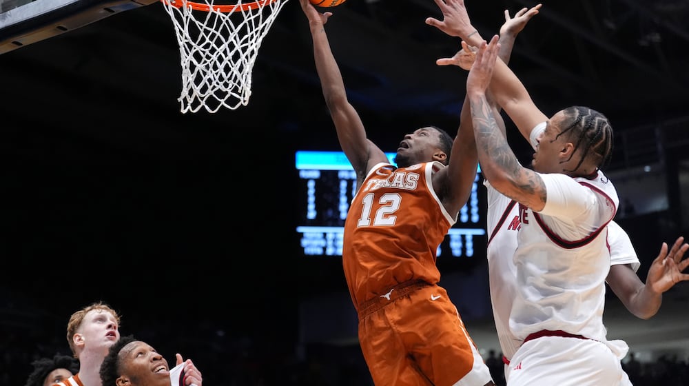 Texas guard Tramon Mark (12), center, scores a layup as North Carolina State forward Darrion Williams (1), right, defends during the first half in a First Four college basketball game in the NCAA Tournament, Tuesday, March 17, 2026, in Dayton, Ohio. (AP Photo/Kareem Elgazzar)