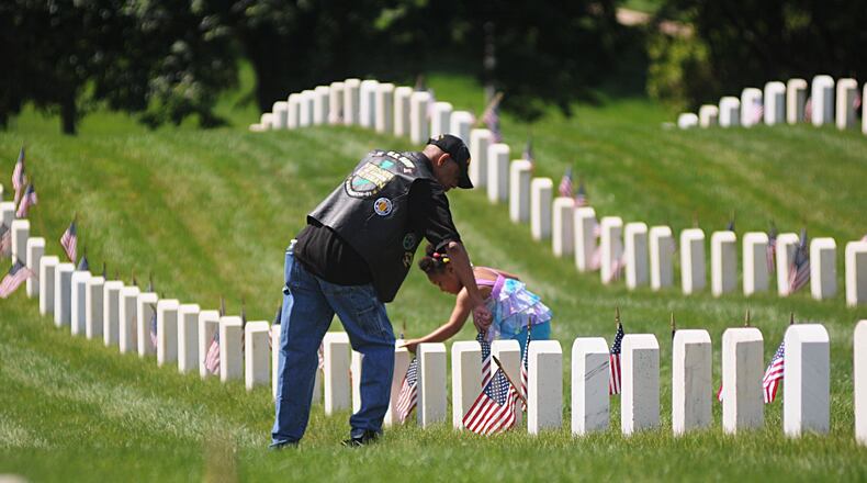 Army retired major Gary S. Conley gets help from his granddaughter, Kailynne Conley, 4, straightening flags at the Dayton National Cemetery on Memorial Day, May 30, 2016.