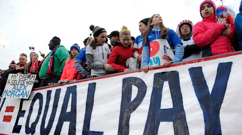 In this April 6, 2016, file photo, fans stand behind a large sign for equal pay for the women’s soccer team during an international friendly soccer match between the United States and Colombia at Pratt & Whitney Stadium at Rentschler Field in East Hartford, Conn. Although weekly earnings for all full-time, salaried workers was up sharply in the first three months of the year, gender and racial pay gaps persist. (AP Photo/Jessica Hill)