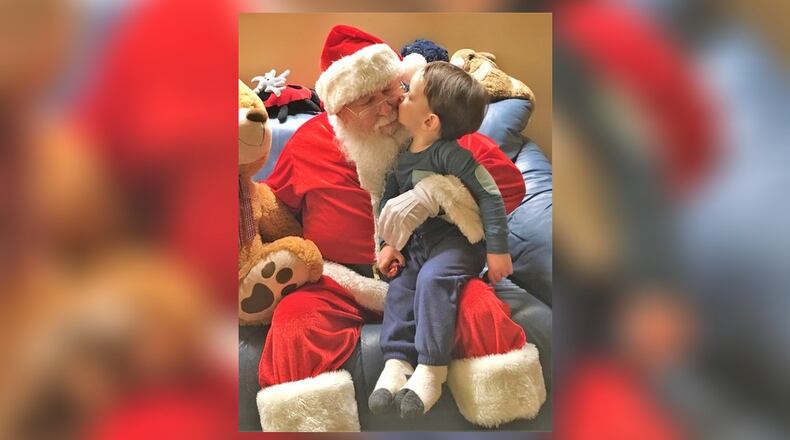 Detlef Frank, as Santa, sits with his grandson Calvin Hoppe. Frank is known in the Dayton area for playing the role of Santa Claus for the past 21 years. CONTRIBUTED