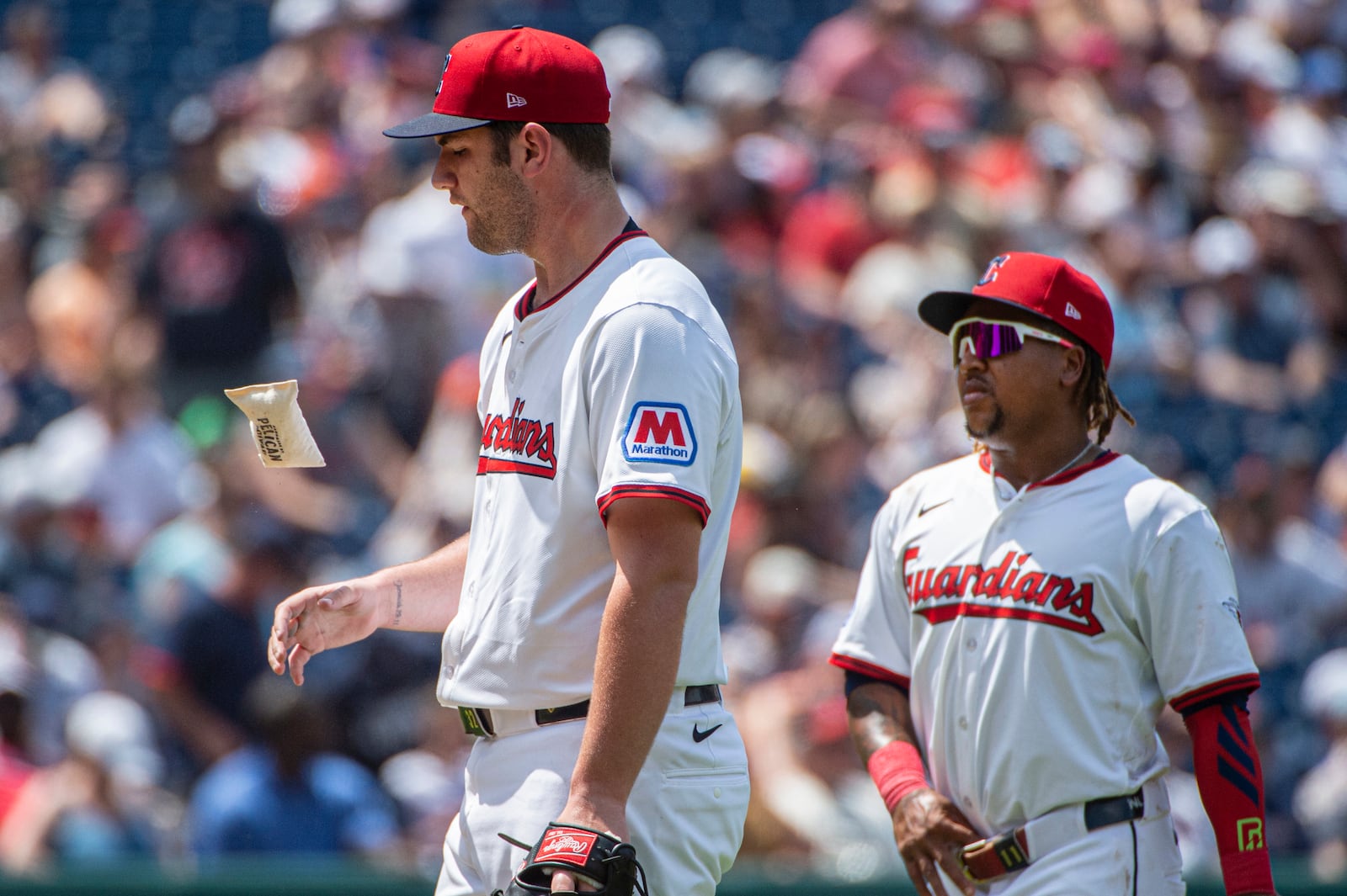 Cleveland Guardians starting pitcher Gavin Williams, left, flips a rosin bag as Jose Ramirez, right, looks on during the fifth inning of a baseball game against the Detroit Tigers, Sunday, July 6, 2025, in Cleveland. (AP Photo/Phil Long)