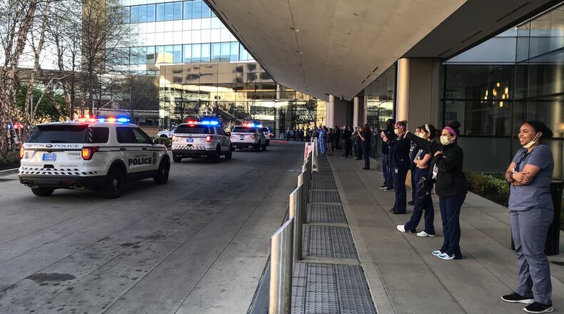 Miami Valley Hospital workers stand outside Tuesday evening, April 21, 2020, as first responders parade around the hospital campus to honor the front line health care workers in the coronavirus pandemic. JIM NOELKER / STAFF