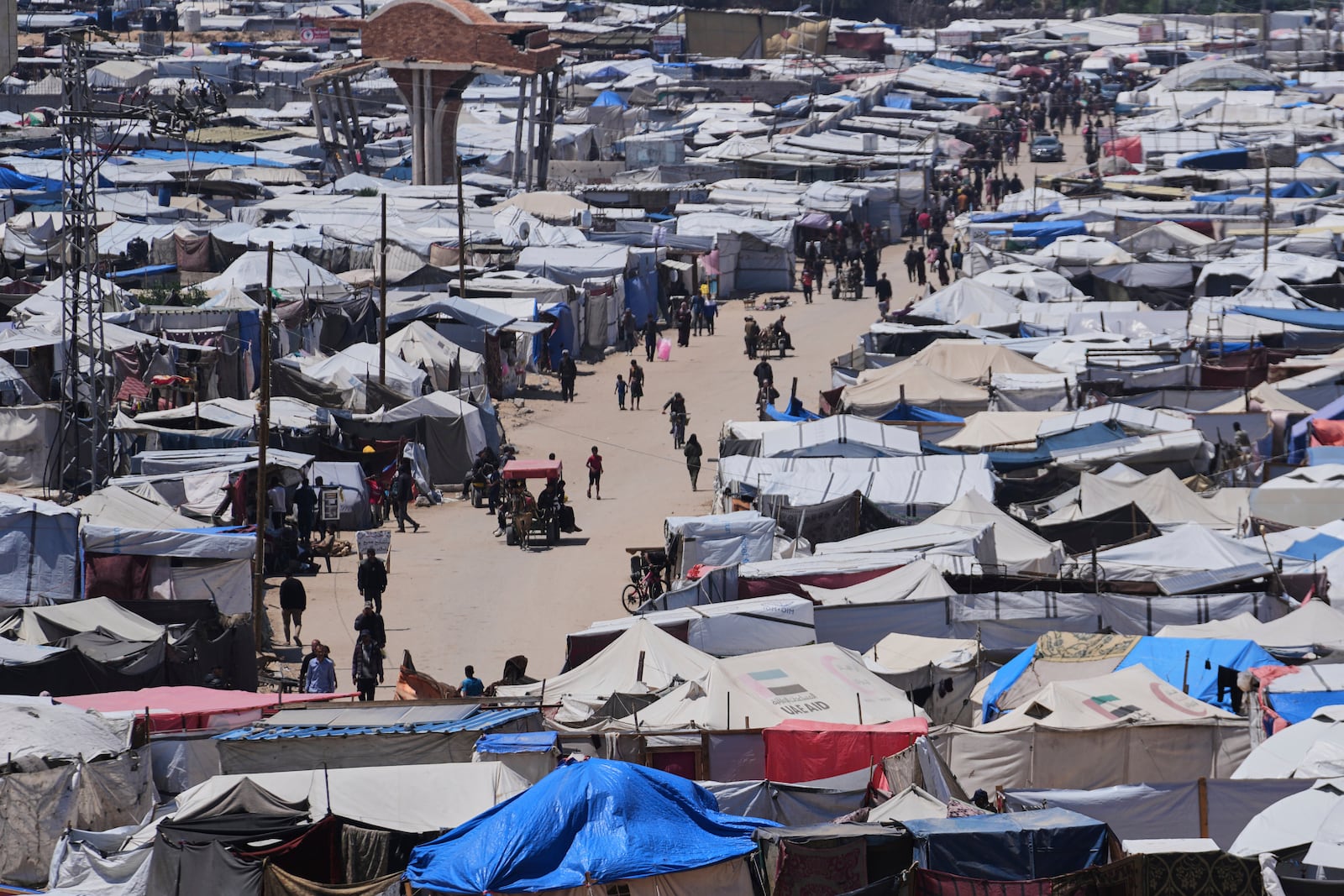 Displaced Palestinians walk through a makeshift tent camp in the Muwasi area of Khan Younis, in the Gaza Strip, on Monday, May 5, 2025. (AP Photo/Abdel Kareem Hana)