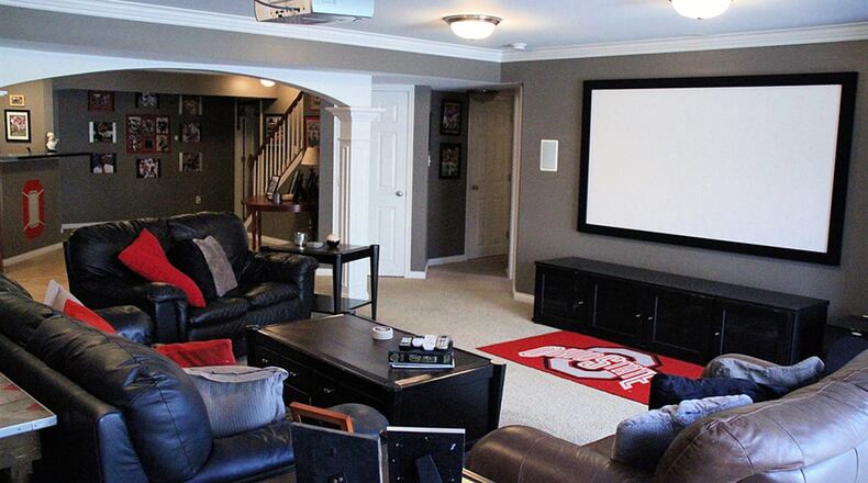 The finished walkout lower level offers bar seating around a wet bar, which could serve as a kitchenette. Square pillars support a wide archway leading into the open recreation area, which incorporates a dedicated theater room and connects to the outdoor patio.