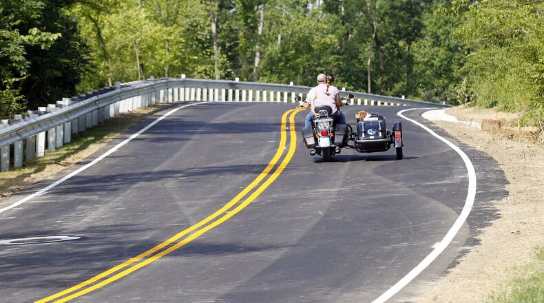 A dog rides sidecar with its owners over the recently opened Lower Miamisburg Road west of Miamisburg. The twisty hillside stretch was rebuilt over the past year after part of the road collapsed. TY GREENLEES / STAFF