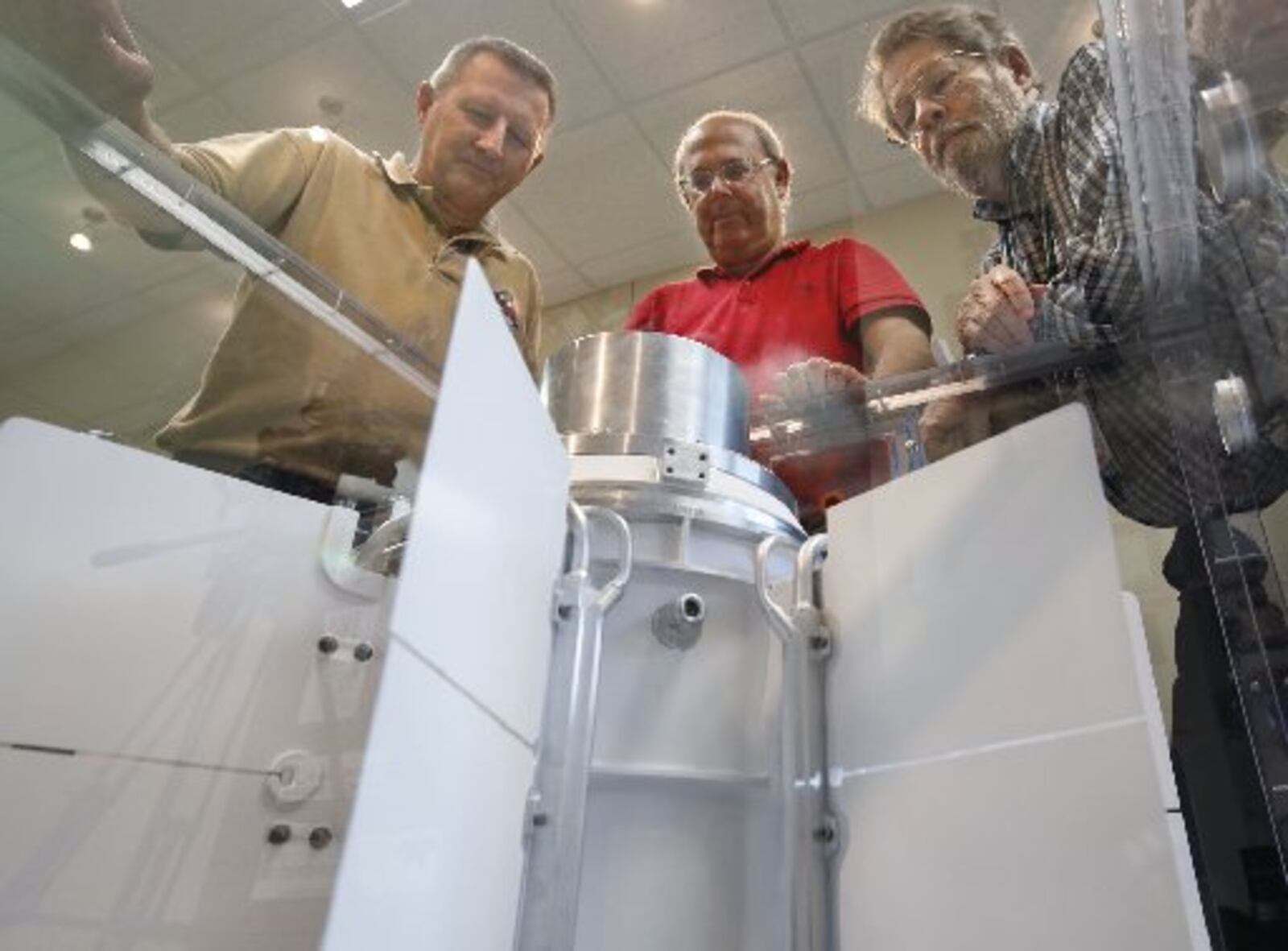 University of Dayton Research Institute scientists and engineers Chadwick Barklay, left, Daniel Kramer and Richard Harris observe a Multi-Mission Radioisotope Thermoelectric Generator that converts the heat from the natural decay of a plutonium-238 dioxide to electricity through solid-state thermoelectric couples. Their laboratory is testing two of the MMRTG units that are cousins of the of Cassini mission power unit assembled in Dayton. TY GREENLEES / STAFF