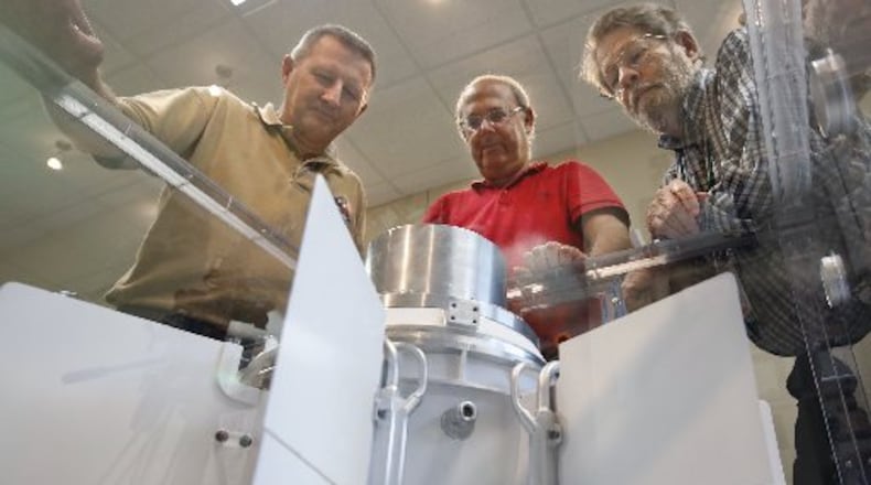 University of Dayton Research Institute scientists and engineers Chadwick Barklay, left, Daniel Kramer and Richard Harris observe a Multi-Mission Radioisotope Thermoelectric Generator that converts the heat from the natural decay of a plutonium-238 dioxide to electricity through solid-state thermoelectric couples. FILE