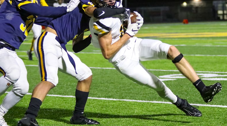 Centerville High School wide receiver Will Linkhart is tackled by Springfield's Dayveon Bates (3) and Delian Bradley (36)  on Thursday night at Springfield High School. The Wildcats won 41-28. CONTRIBUTED PHOTO BY MICHAEL COOPER