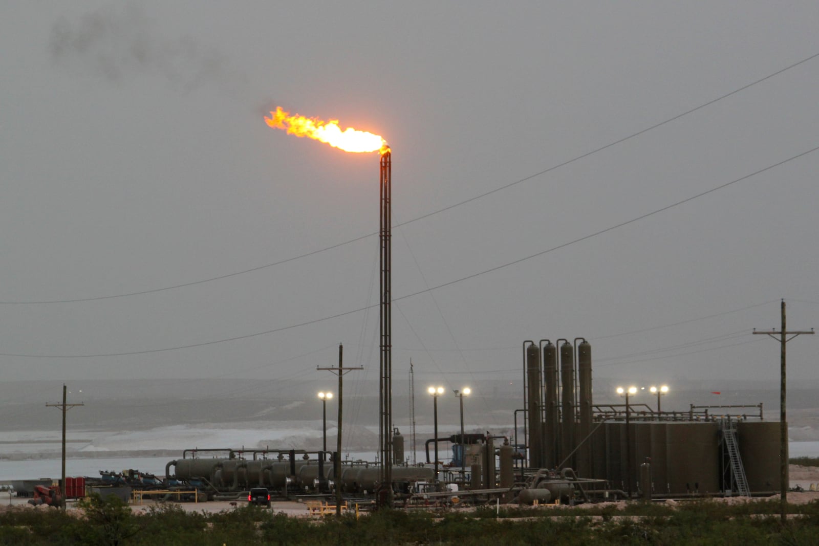 Strong winds kick up dust as a facility in the Permian Basin flares natural gas east of Carlsbad, N.M., on Monday, May 19, 2025. (AP Photo/Susan Montoya Bryan)