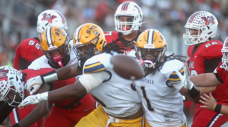 Springfield defensive players and Wayne offensive players eye a loose football in the first half on Friday, Oct. 3, 2025, at Heidkamp Stadium in Huber Heights. The play was rule dead, so there was no fumble. David Jablonski/Staff