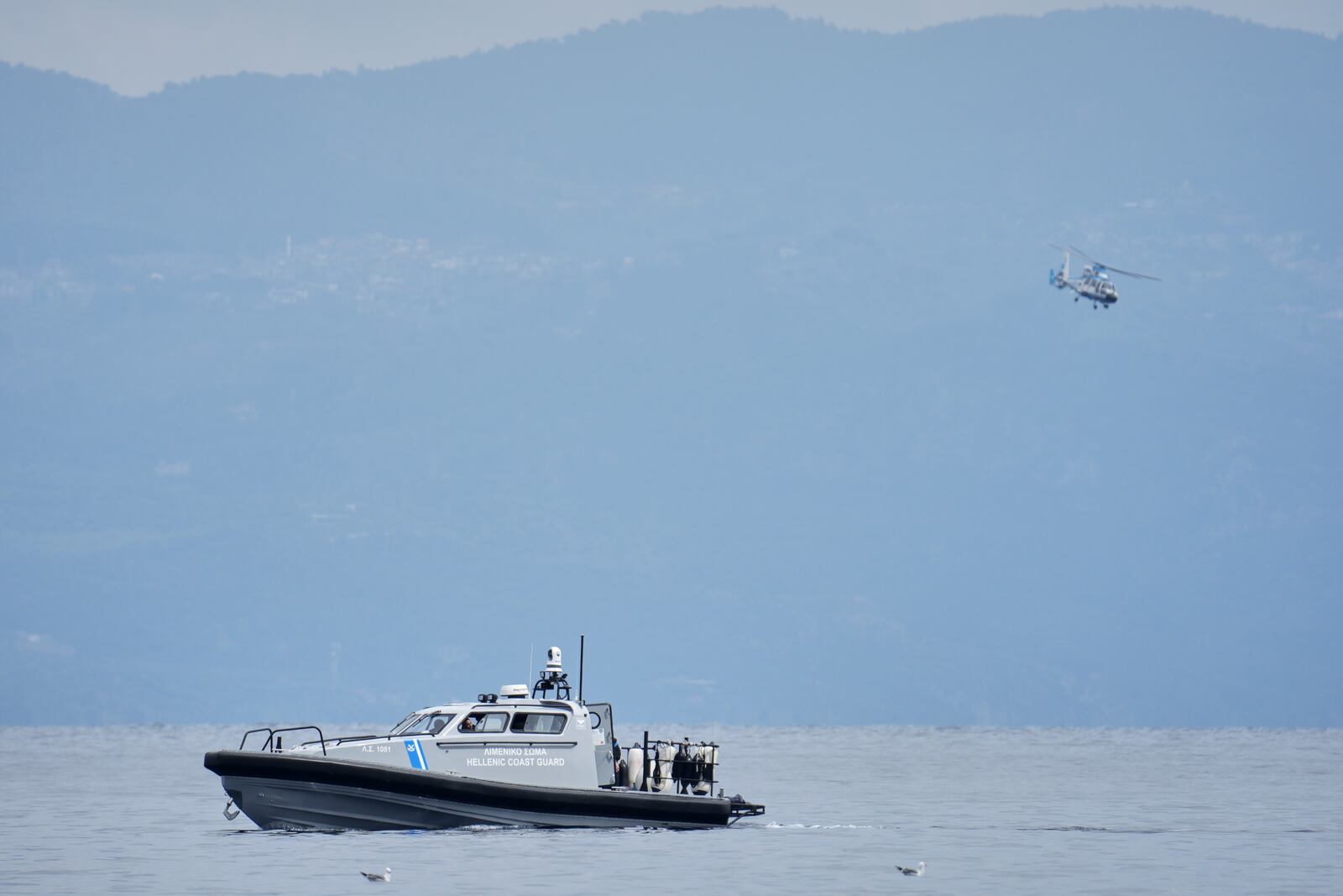 A Greek coast guard vessel and a helicopter take part in a search and rescue operation, after the capsizing of a boat carrying migrants, off the coast on the northeastern Aegean Sea island of Lesbos, Greece, Thursday, April 3, 2025. (AP Photo/Panagiotis Balaskas)