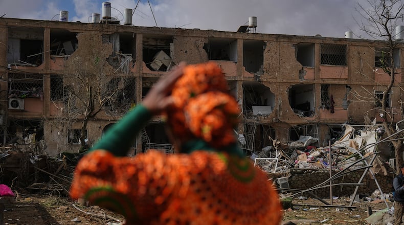 People survey a site that was struck by an Iranian missile in Dimona, southern Israel, Sunday, March 22, 2026. (AP Photo/Ariel Schalit)