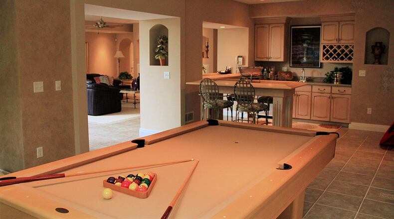 Relaxing and recreational options abound on the lower level. Inset carpet covers the floor in the sitting area, which connects to the equipped wet bar/kitchenette via a pass-through window.