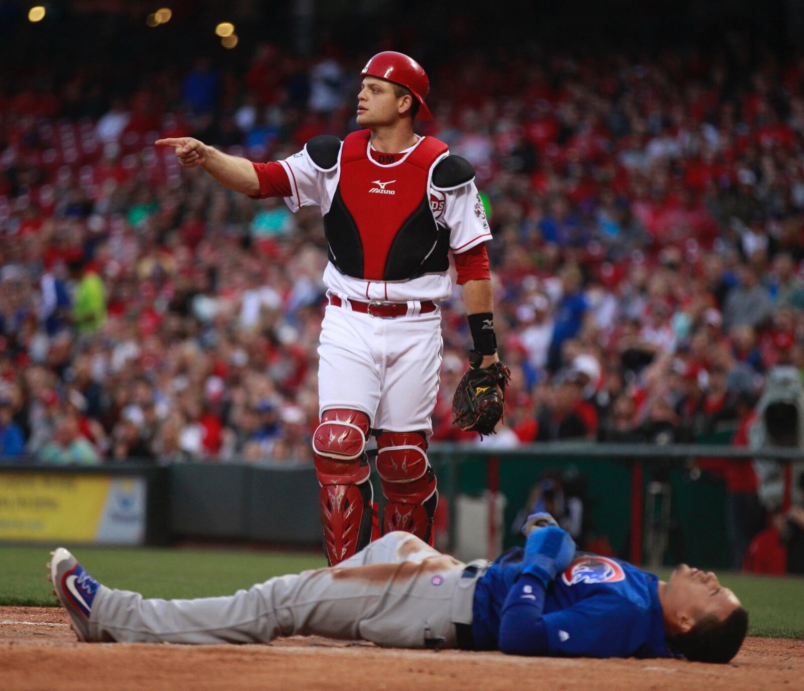 The Cubs’ Javier Baez lies on the ground after scoring on a hard slide against Reds catcher Devin Mesoraco on Friday, April 22, 2016, at Great American Ball Park in Cincinnati. David Jablonski/Staff