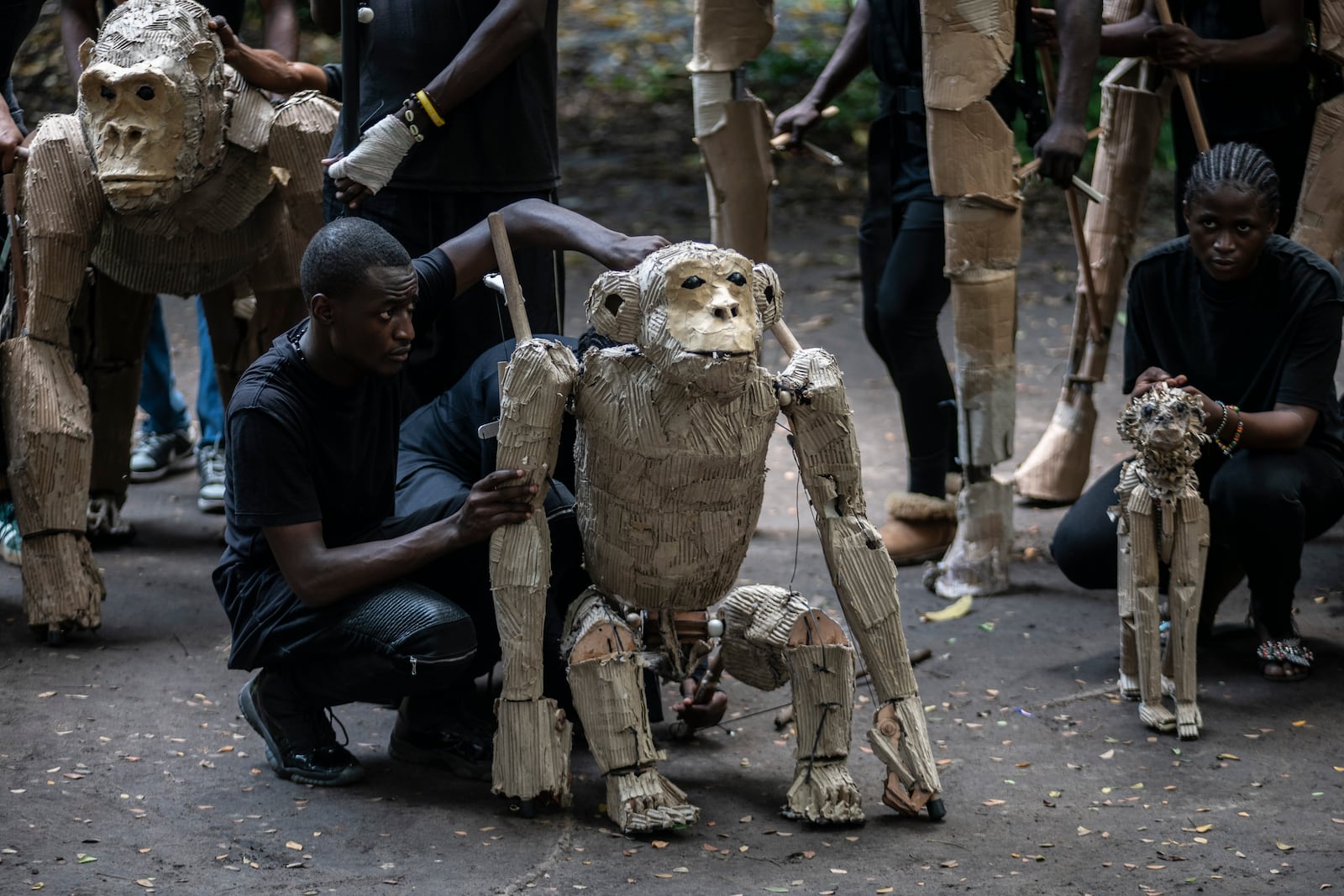 Puppeteers move cardboard animals through DRC's capital Kinshasa's botanical gardens Thursday, April 10, 2025, the first steps of "The Herds", a moving theatre performance that will travel from the Democratic Republic of the Congo to the Arctic Circle in a bid to bring attention to the climate crisis. (AP Photo/Samy Ntumba Shambuyi)