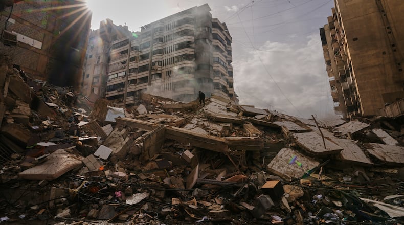 A man stands atop the rubble as smoke rises from a building destroyed in an Israeli airstrike in Dahiyeh, Beirut's southern suburbs, Lebanon, Saturday, March 14, 2026. (AP Photo/Hassan Ammar)