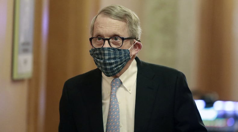 In this April 16, 2020, file photo wearing his protective mask made by his wife, Ohio Gov. Mike DeWine walks into his daily coronavirus news conference at the Ohio Statehouse in Columbus, Ohio. (Doral Chenoweth/The Columbus Dispatch via AP)