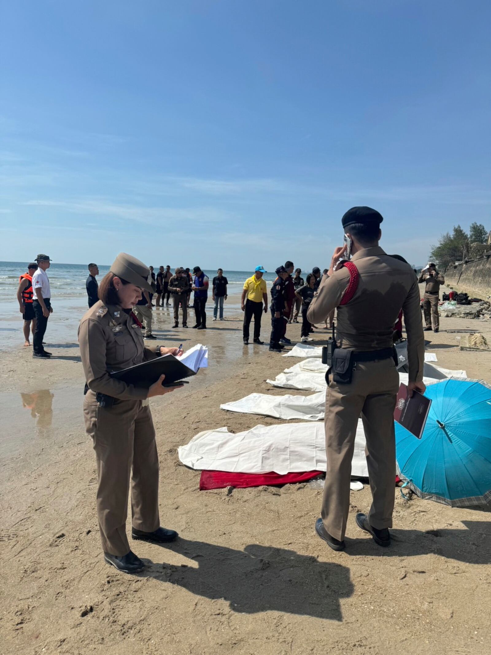 In this photo provided by the Royal Thai Police, police officers investigate the scene after a small police plane crashed into the sea, killing multiple people on board, in Prachuab Kiri Khan province, western of Thailand, Friday, April 25, 2025. (Royal Thai Police via AP)
