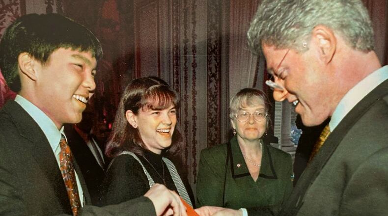 John Kim gives Bill Clinton his family's Christmas card as Julie Waszczak and Maija Recevskis look on. (CONTRIBUTED)