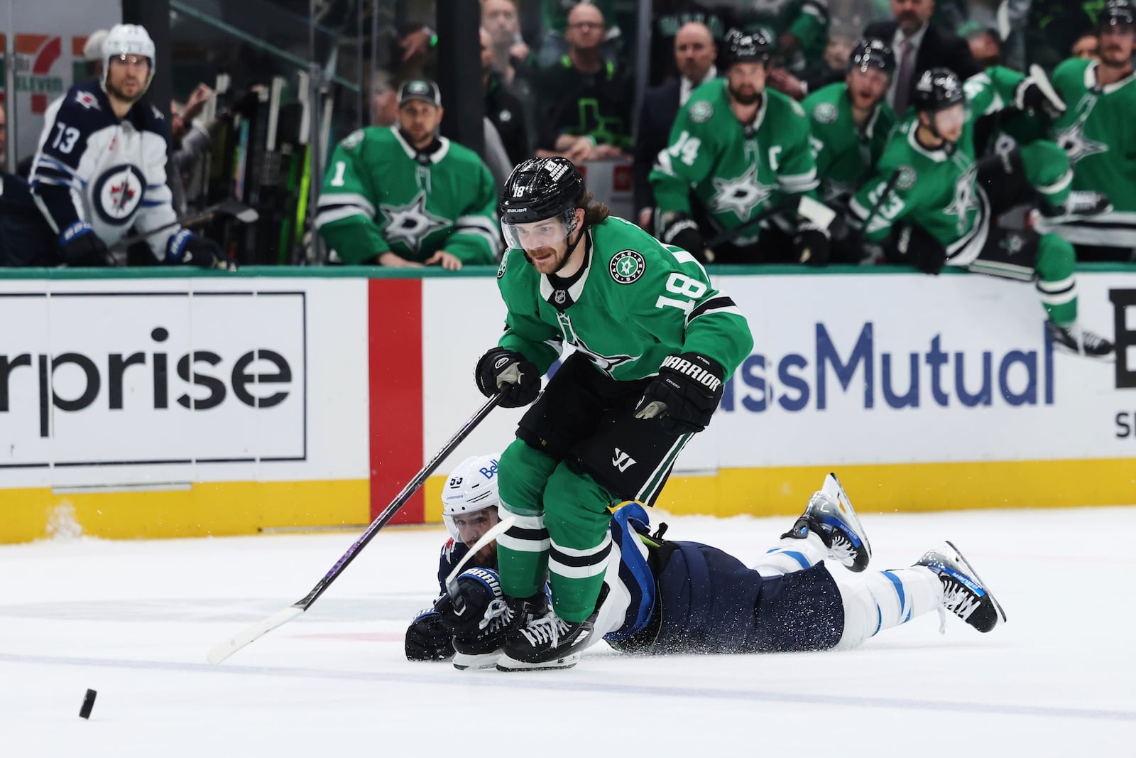 Dallas Stars' Sam Steel (18) is tripped by Winnipeg Jets' Mark Scheifele as Steel chases after the puck in the third period of Game 6 of a second-round NHL hockey playoff series in Dallas, Saturday, May 17, 2025. (AP Photo/Gareth Patterson)