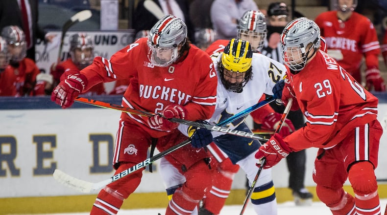 Ohio State's Gustaf Westlund (29) and Ryan O'Connell (24) try to keep Michigan's Michigan's Nolan Moyle (27) away from the puck during a college hockey game Sunday, March 14, 2021, in South Bend, Ind. (Michael Caterina/South Bend Tribune via AP)