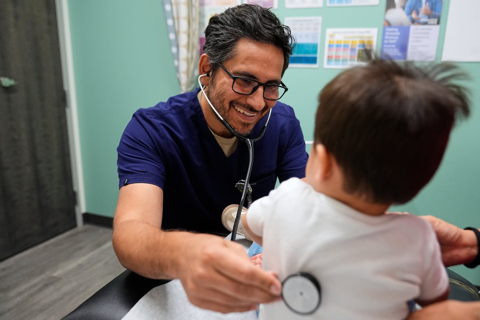 Pediatrician Irving Phillips, left, examines a 16-month-old boy at a CommuniCARE+OLE clinic Thursday, June 26, 2025, in Davis, Calif. (AP Photo/Godofredo A. Vásquez)