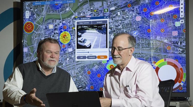 In this 2016 file photo, Larrell Walters, then-Universal Technology Corp’s senior director of commercial products, left, and company CEO Joe Sciabica are reviewing a law enforcement data mapping system called Footprint. In the COVID-19 era, the challenging work of defense contractors has become even more challenging. FILE
