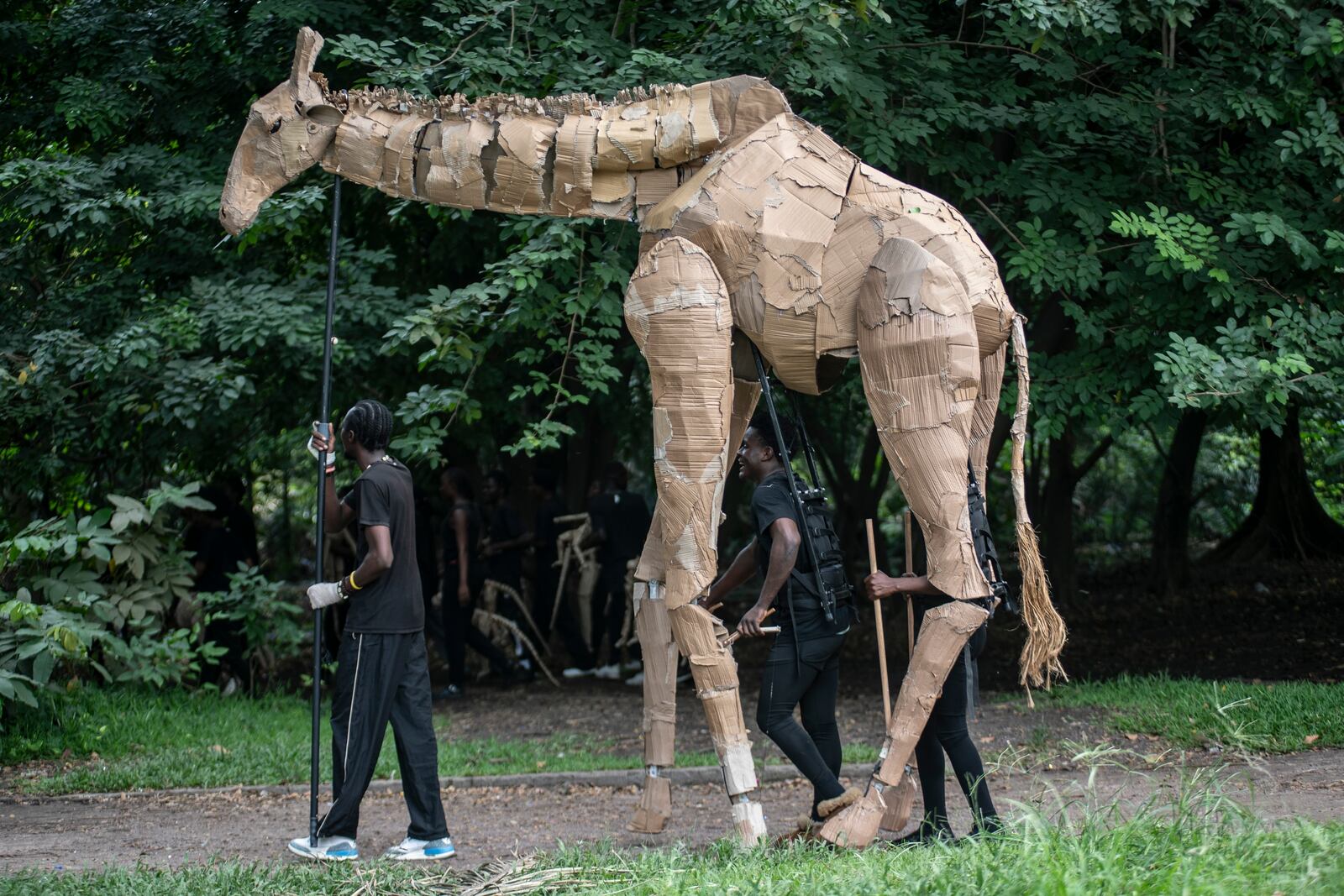 Puppeteers move cardboard animals through DRC's capital Kinshasa's botanical gardens Thursday, April 10, 2025, the first steps of "The Herds", a moving theatre performance that will travel from the Democratic Republic of the Congo to the Arctic Circle in a bid to bring attention to the climate crisis. (AP Photo/Samy Ntumba Shambuyi)