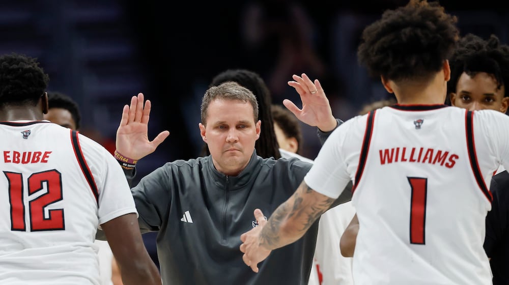 NC State head coach Will Wade, center, greets center Scottie Ebube (12) and forward Darrion Williams (1) as they walk to the bench during a timeout in the second half of an NCAA college basketball game against Pittsburgh in the second round of the Atlantic Coast Conference tournament in Charlotte, N.C., Wednesday, March 11, 2026. (AP Photo/Nell Redmond)