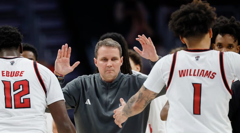 NC State head coach Will Wade, center, greets center Scottie Ebube (12) and forward Darrion Williams (1) as they walk to the bench during a timeout in the second half of an NCAA college basketball game against Pittsburgh in the second round of the Atlantic Coast Conference tournament in Charlotte, N.C., Wednesday, March 11, 2026. (AP Photo/Nell Redmond)