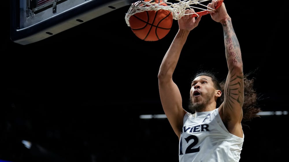 Xavier forward Tre Carroll (12) dunks the ball during the fist half of an NCAA college basketball game against UConn, Wednesday, Dec. 31, 2025, in Cincinnati. (AP Photo/Carolyn Kaster)