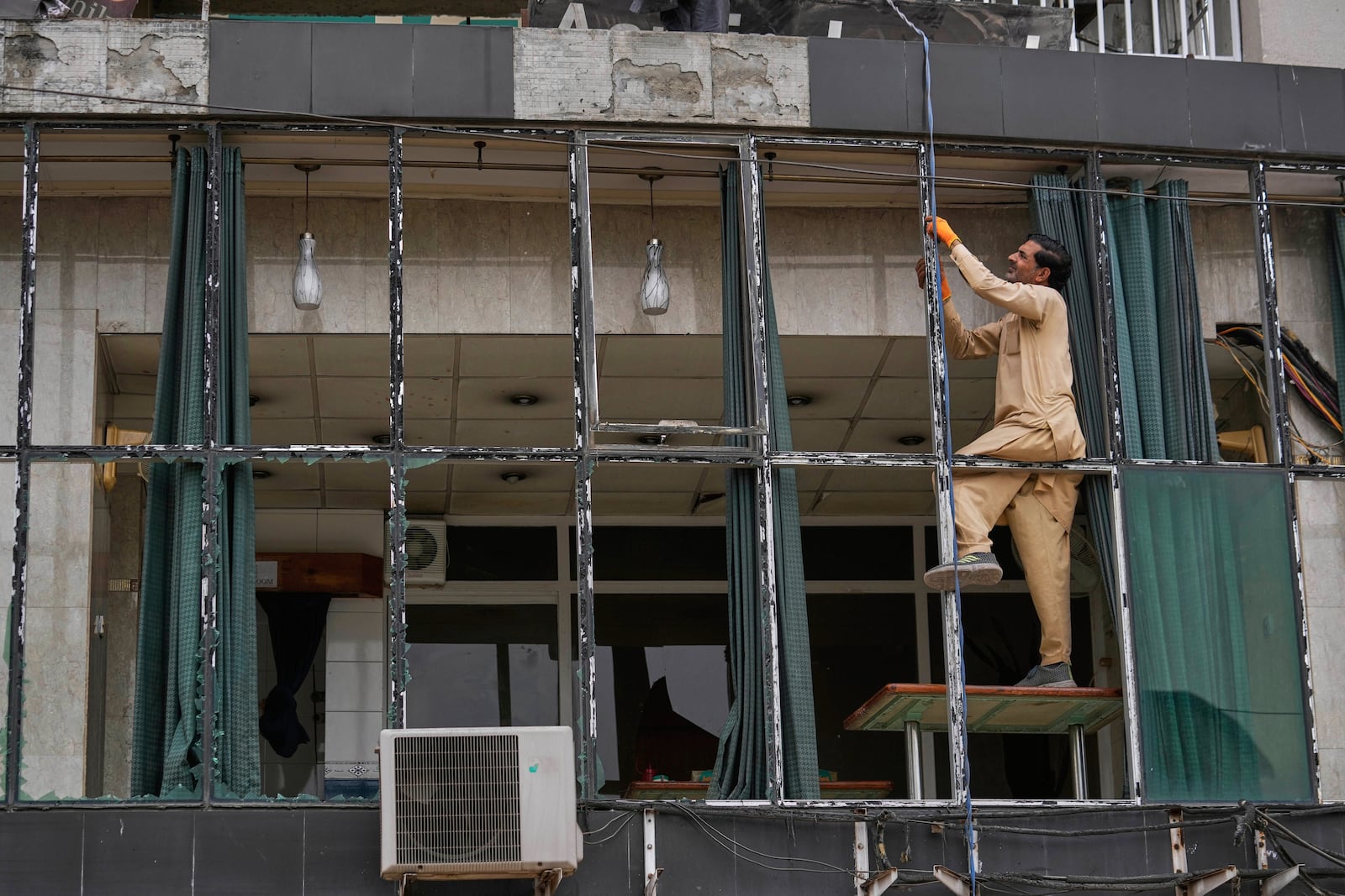 A worker repairs broken glass of a building at the parking area of Rawalpindi Cricket Stadium, where a suspected Indian drone was crashed on Thursday, in Rawalpindi, Pakistan, Friday, May 9, 2025. (AP Photo/Anjum Naveed)