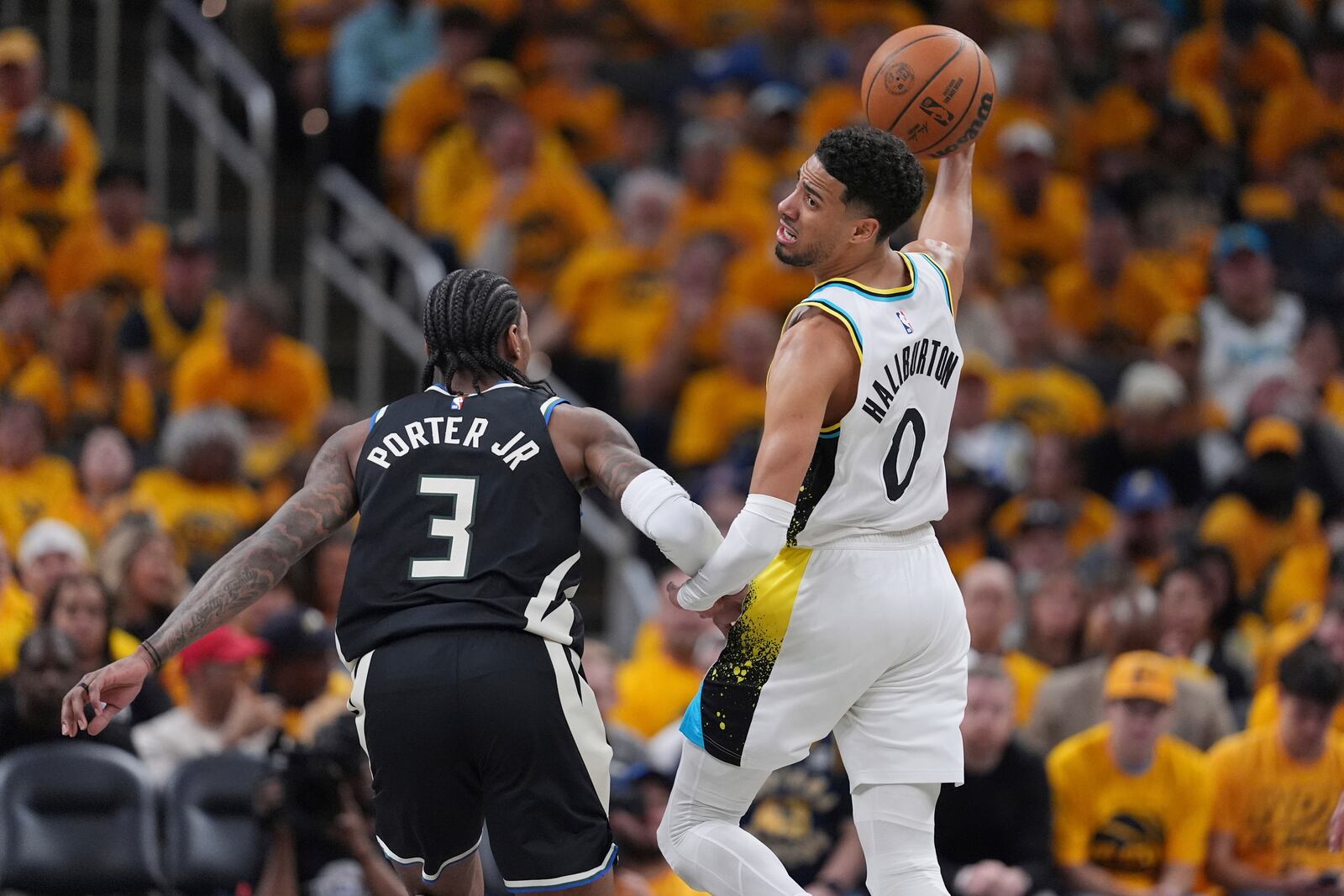 Indiana Pacers' Tyrese Haliburton (0) looks to pass as Milwaukee Bucks' Kevin Porter Jr. (3) defends during the second half of a first-round NBA basketball playoff game, Saturday, April 19, 2025, in Indianapolis. (AP Photo/Michael Conroy)