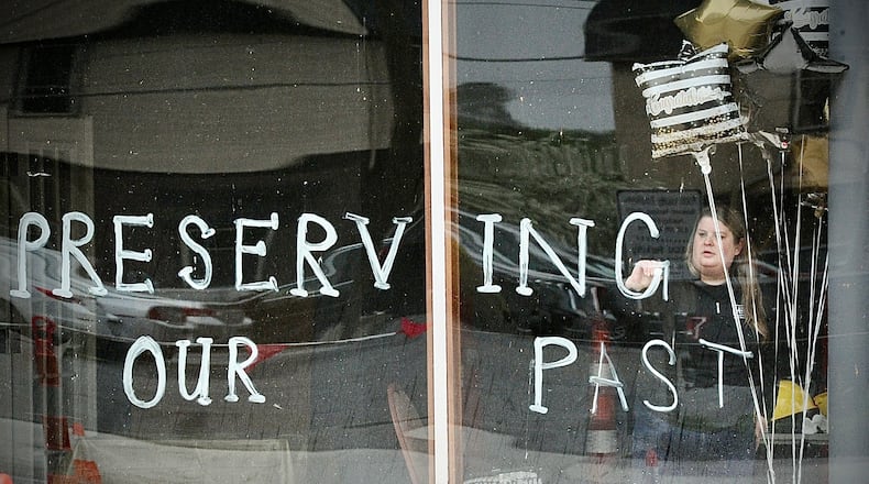 Julie Carter, a member of the Troy Historic Preservations Alliance, writes on the windows of the Tavern / IOOF / Old Courthouse building Friday April 19, 2024. West Main Street in front of the building was reopened to traffic Friday after a near 10-month closure. MARSHALL GORBY\STAFF