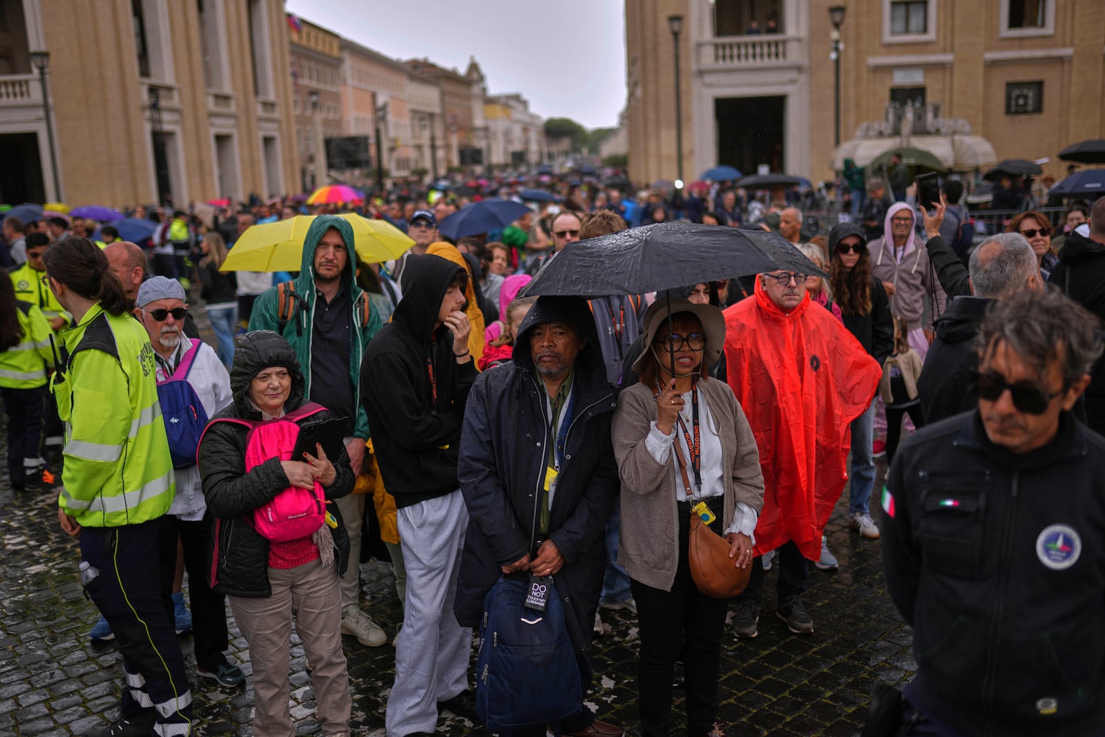 People wait in line under the rain to enter St. Peter's Basilica to view Pope Francis lying in state, at the Vatican, Thursday, April 24, 2025. (AP Photo/Francisco Seco)
