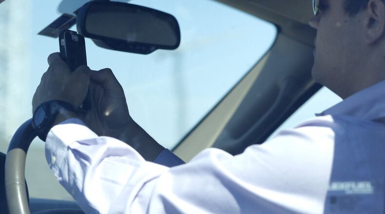A man looks at his phone while driving down Woodall Rodgers Freeway on July 16, 2015, in Dallas, Texas. Drivers should never take their eyes off the road for more than two seconds at a time, the National Highway Traffic and Safety Administration says. (Rose Baca/Dallas Morning News/TNS)