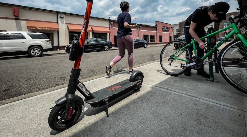 A Spin electric scooter rests outside Panera Bread on Jasper Street in Dayton. JIM NOELKER/STAFF