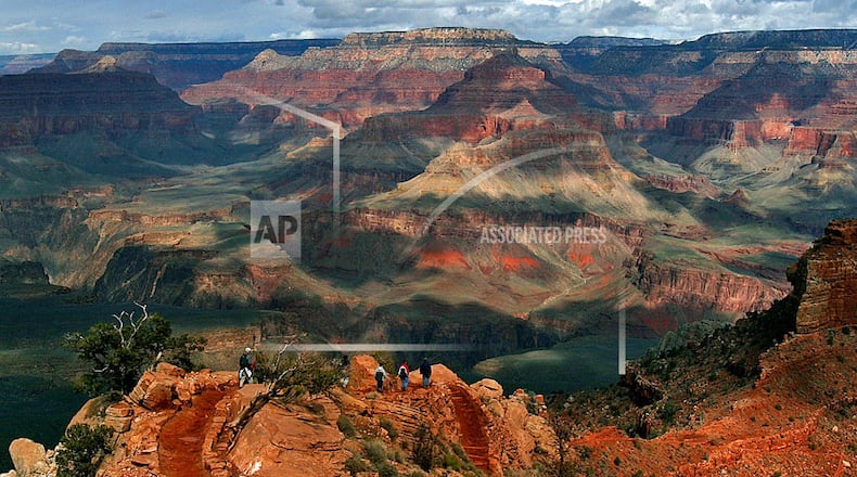 FILE - In this Feb. 22, 2005, file photo, with the North Rim in the background, tourists hike along the South Rim of the Grand Canyon in Grand Canyon, Ariz. Crews are drilling at the bottom of the Grand Canyon to test the idea of shifting the area where water is drawn to serve millions of people at the parkâs popular South Rim. The national parkâs water supply comes from a natural spring that flows through 12.5 miles of pipeline. But the 1960s aluminum pipeline to the South Rim twists and turns around trails and through rocky terrain, frequently breaking and leaking.  (AP Photo/Rick Hossman, File)