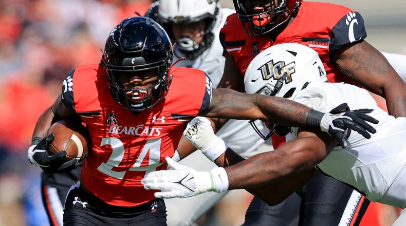 Cincinnati running back Jerome Ford (24) carries the ball as he breaks a tackle against UCF linebacker Jeremiah Jean-Baptiste, right, during the first half of an NCAA college football game, Saturday, Oct. 16, 2021, in Cincinnati. (AP Photo/Aaron Doster)
