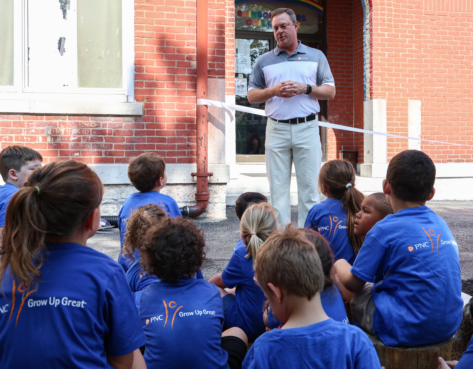 PNC regional president for Dayton David Melin talks to children at Rainbow Years Child Care during a ceremony celebrating an outdoor playground at the center on South Smithville Road in Dayton on Wednesday, June 25. The PNC Foundation funded the playground.  BRYANT BILLING / STAFF